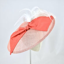 Load image into Gallery viewer, Wide saucer in coral sinamay with coral silk bow and white feathers on a bandeau base. 3/4 front view.
