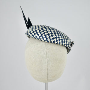 Short brimmed perching cap made in navy and white buntal straw with feathers.  Rear view.