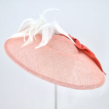 Load image into Gallery viewer, Wide saucer in coral sinamay with coral silk bow and white feathers on a bandeau base. Back view.