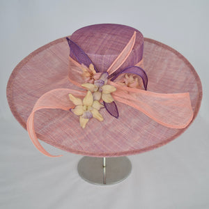 Coral and amethyst sinamay with sinamay ribbons and handmade flowers.  Side view.
