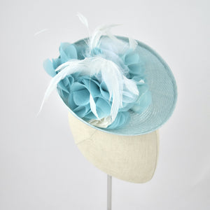 Saucer hat in ice blue parisisal with silk and feather trim.  3/4 front view.