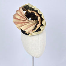 Load image into Gallery viewer, A sculptural fascinator hat with pleated gold fabric on black sinamay, displayed on a cream-colored mannequin head against a light gray background.
