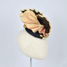 Load image into Gallery viewer, A sculptural fascinator hat with pleated gold fabric on black sinamay, displayed on a cream-colored mannequin head against a light gray background.
