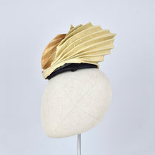 Load image into Gallery viewer, A sculptural fascinator hat with pleated gold fabric on black sinamay, displayed on a cream-colored mannequin head against a light gray background.
