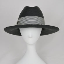 Load image into Gallery viewer, A black straw fedora hat with a black and white striped band, displayed on a white mannequin head against a light gray background.
