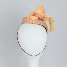 Load image into Gallery viewer, A peach colored fascinator hat made with vintage straw and curled feathers, displayed on a mannequin head.
