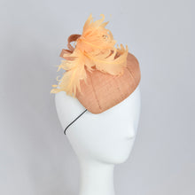 Load image into Gallery viewer, A peach colored fascinator hat made with vintage straw and curled feathers, displayed on a mannequin head.
