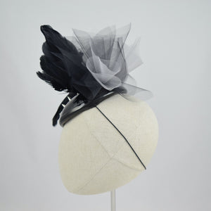 Cocktail hat in wet look vinyl with feathers, tulle, and studs. Side view.