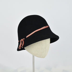 Black fur felt with narrow coral colored ribbon in a classic cloche style. 3/4 side view.