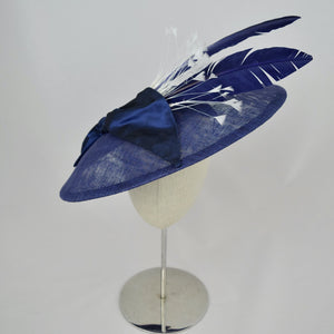 Royal blue sinamay saucer with silk bow and hand dyed feathers on a bandeau base.