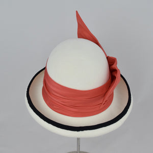 Winter white velour felt bowler with a pleated trim of coral colored silk and black grosgrain ribbon. Back view.