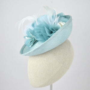 Saucer hat in ice blue parisisal with silk and feather trim. Side view.