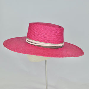 Shocking pink panama straw with a telescope crown and wide, flat brim. Side view.